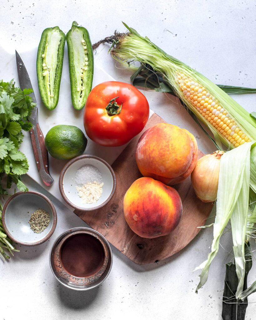 fresh peach salsa ingredients: peaches, tomato, corn, jalapeño, onion, lime cilantro, hot sauce, spices