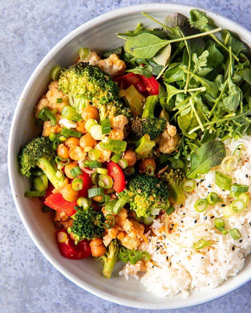 Orange chickpeas and vegetables with rice and greens
