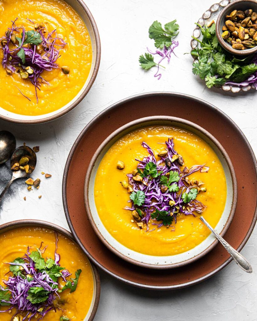 3 bowls with butternut squash soup and toppings